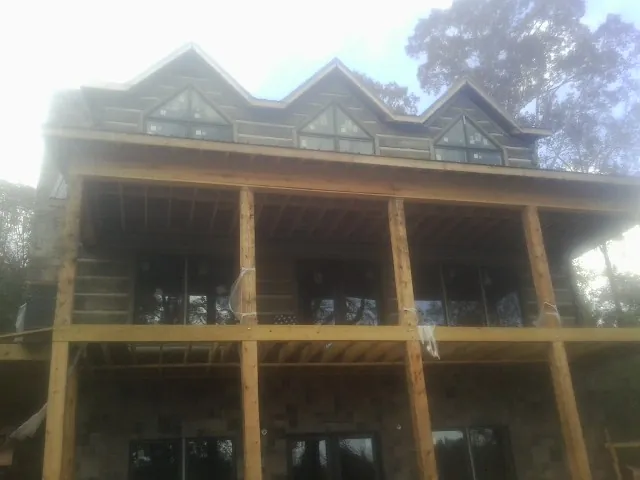 Dormers and porch framing on a large log home under construction — Roof Coating work by our crew in Roma